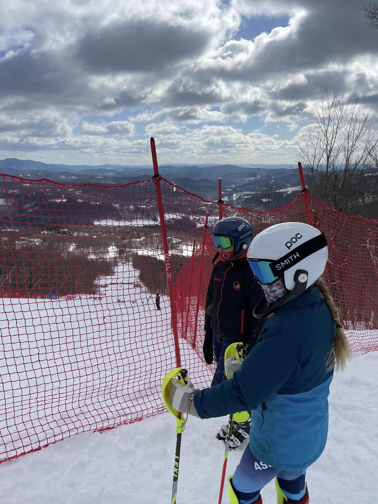 Two skiers standing on the mountain looking downward