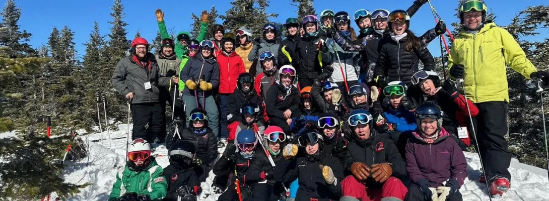 U14 Skiers sitting on the snow posing together for a picture