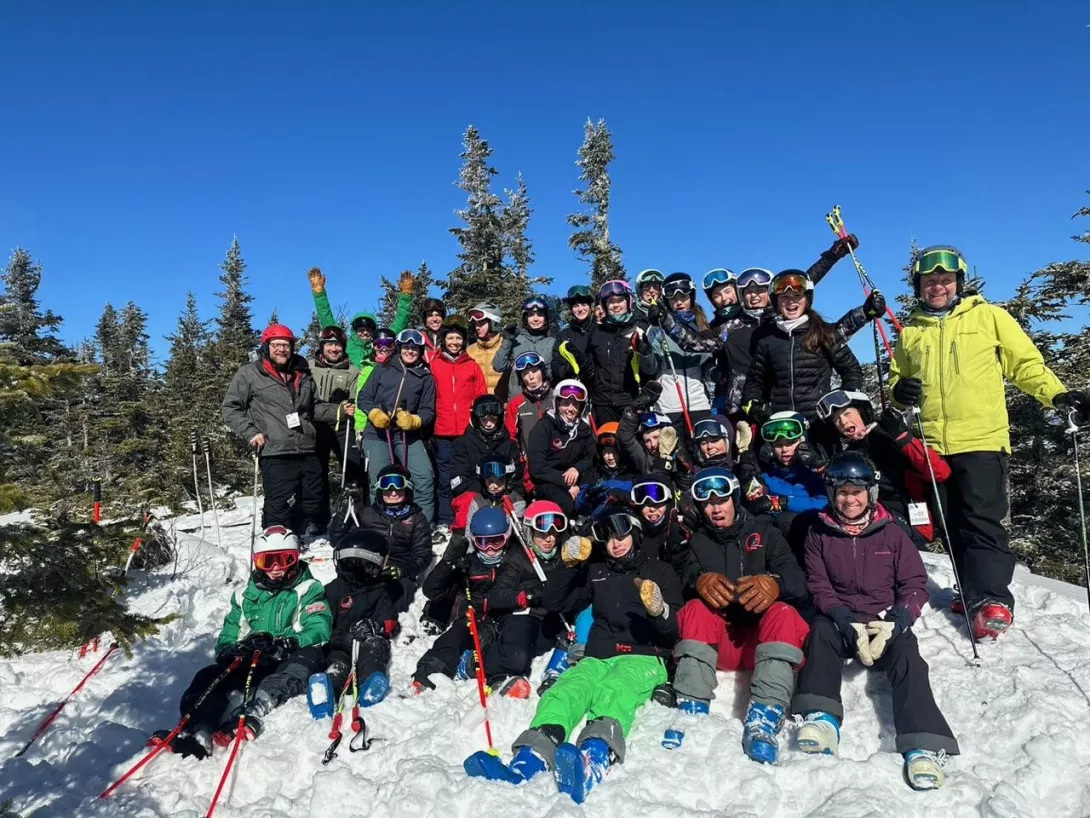 U14 Skiers sitting on the snow posing together for a picture